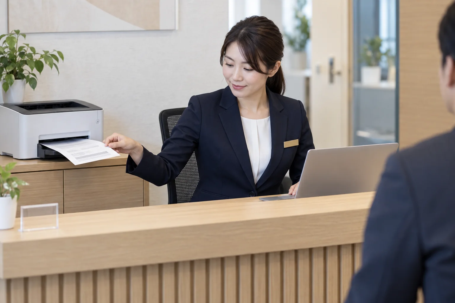 受付で小型の印刷専用プリンターから書類を取り出す担当者